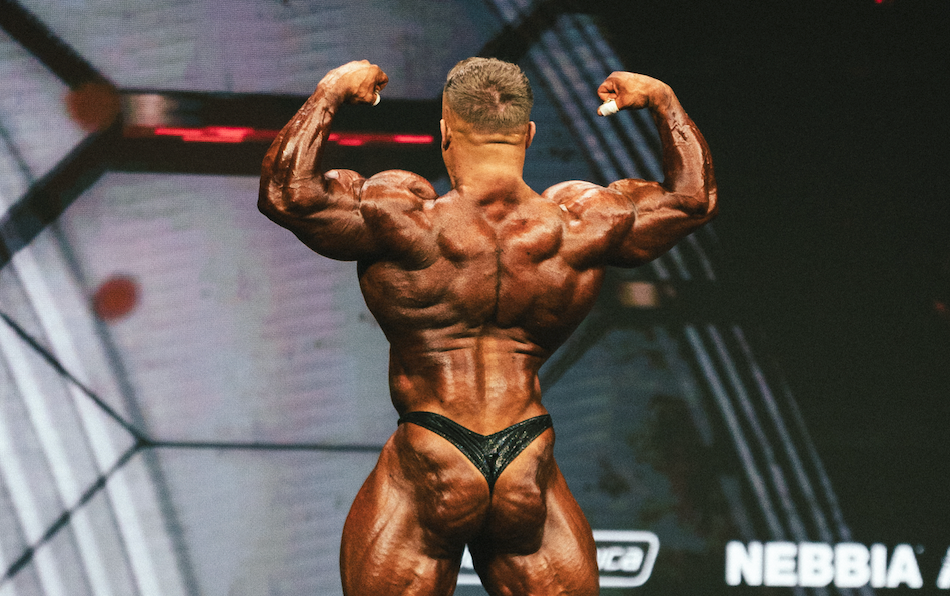 Urs Kalecinski zeigt seine Muskeldefinition bei einem Bodybuilding Wettkampf auf der Bühne – Fokus auf Muskelaufbau, Posing und Wettkampfvorbereitung